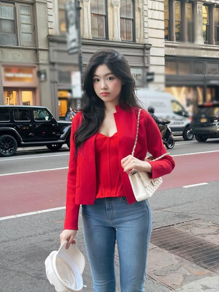 Lọ Lem tạo điểm nhấn bằng áo corset đỏ phối blazer đồng màu, quần jeans và túi sáng màu. Sắc đỏ khiến diện mạo nổi bật hơn bảng màu pastel thường thấy. Mái tóc đen tạo độ tương phản với trang phục, đồng thời làm rõ làn da sáng và đường nét gương mặt. (Ảnh: FB Mai Thảo Linh)
