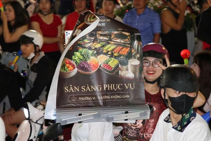 Tranh thủ “quảng cáo” giữa dòng người ăn mừng.
