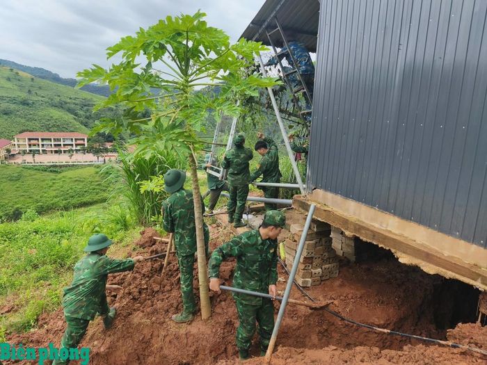 Cán bộ, chiến sĩ Đồn Biên phòng cửa khẩu quốc tế Lóng Sập giúp hộ gia đình tại bản Bó Sập khắc phục hậu quả sạt lở đất. Ảnh: Quàng Hùng