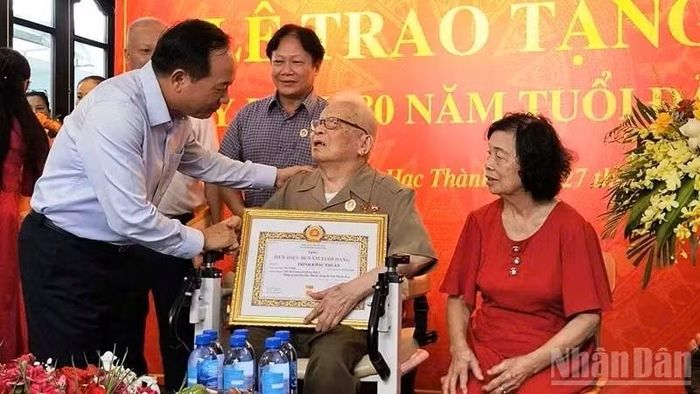 Trưởng Ban Tuyên giáo Trung ương trao Huy hiệu 80 năm tuổi Đảng cho đảng viên Trịnh Khắc Thuần. Ảnh: Nhân dân