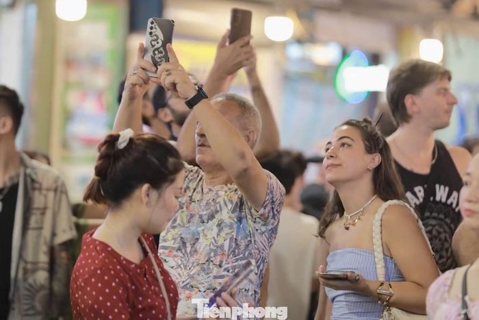 Nhiều người giơ điện thoại ghi lại khoảnh khắc đặc biệt, khi cả khu phố chìm trong sắc đỏ và tiếng reo hò.