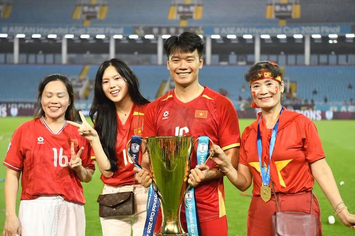 Vợ và người thân có mặt trên sân Mỹ Đình cùng Thành Chung nâng cúp và lưu lại khoảnh khắc lịch sử. Gia đình mặc áo tuyển Việt Nam, đeo huy chương vàng và chia sẻ niềm vui với trung vệ sinh năm 1997. Ảnh: Như Ý.