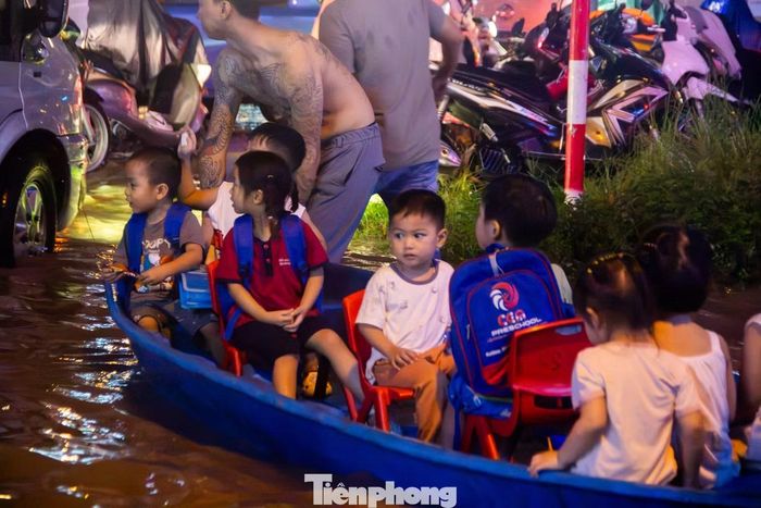Mưa lớn đúng giờ tan tầm gây ngập sâu, đến 19h tối, nhiều phụ huynh vẫn chật vật cõng, bế con nhỏ, thậm chí phải thuê thuyền chở các em qua những vùng nước sâu.