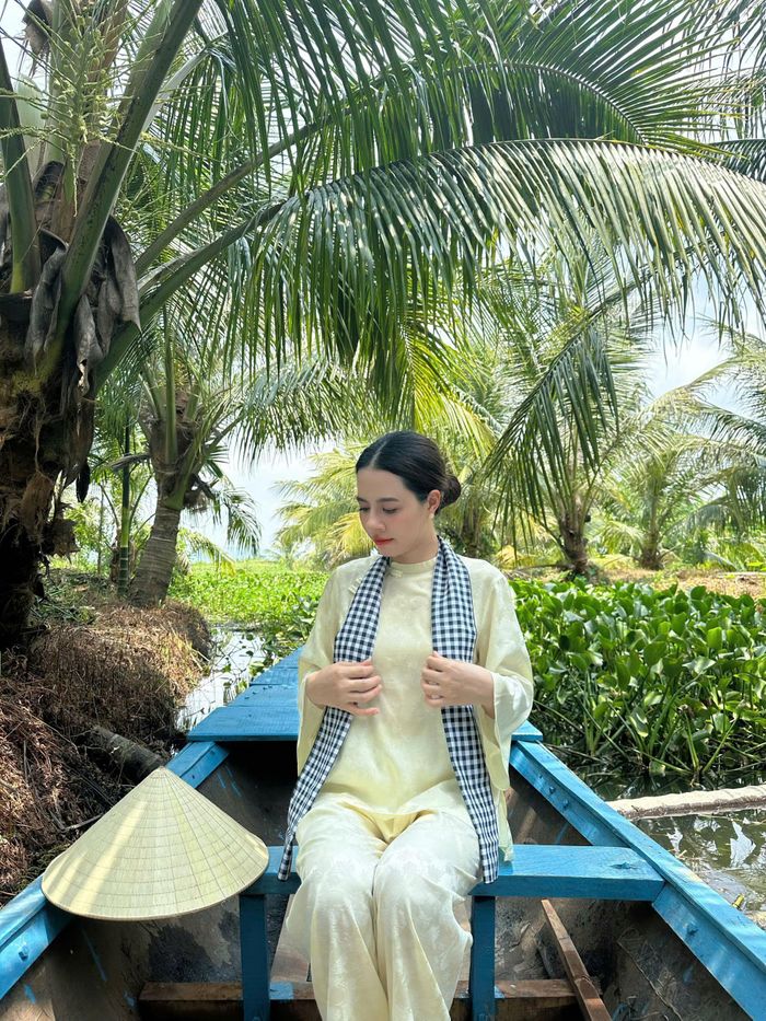 Chị Chi diện áo bà ba, đội nón lá và đeo khăn rằn, chụp ảnh check-in giữa khung cảnh xanh mát. Ảnh: Dương Kim Chi
