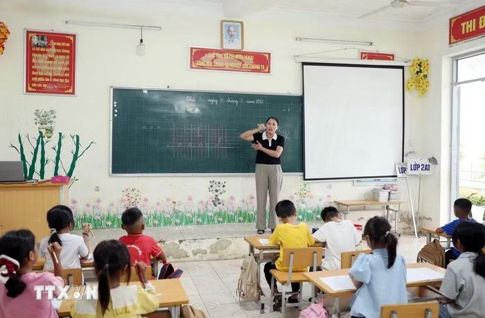 Giáo viên Trường Phổ thông Dân tộc Bán trú Tiểu học và Trung học cơ sở Thu Lũm hướng dẫn học sinh lớp 1 cách cầm bút: (Ảnh: Quý Trung/TTXVN) ​