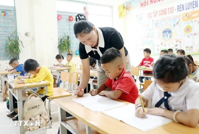 Giáo viên Trường Phổ thông Dân tộc Bán trú Tiểu học và Trung học cơ sở Thu Lũm hướng dẫn học sinh lớp 1 tập viết chữ. (Ảnh: Quý Trung/TTXVN)