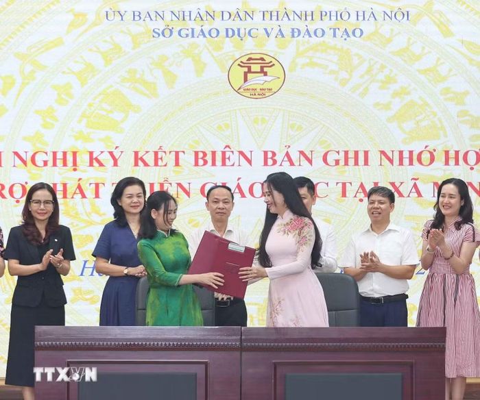 Đại diện Trường Mầm non Minh Châu cùng đại diện Trường Mầm non Hoa Hồng thực hiện ký kết, trao biên bản ghi nhớ hợp tác. (Ảnh: Thanh Tùng/TTXVN)