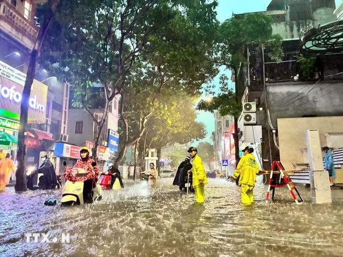Công nhân thoát nước khơi thông dòng chảy trên phố Đội Cấn. (Ảnh: Lê Đông/TTXVN)