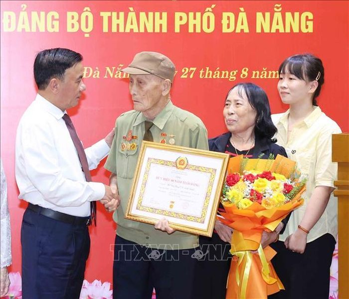 Thường trực Ban Bí thư Trần Cẩm Tú cùng gia đình đảng viên lão thành Hồ Văn Lang. Ảnh: Phương Hoa/TTXVN