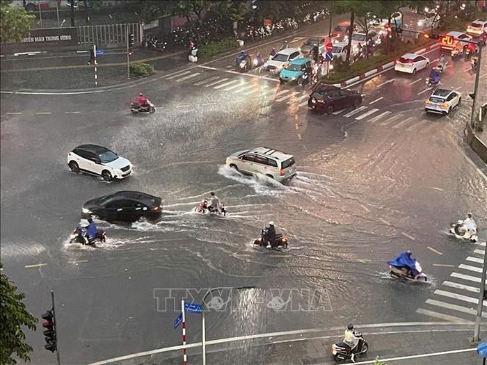 Các phương tiện di chuyển chậm qua các đoạn bị ngập nước trên đường Phạm Văn Bạch. Ảnh: Nguyễn Thắng/TTXVN