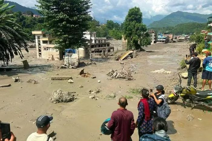 Những du khách may mắn chạy thoát lên núi ngậm ngùi trước cảnh bị lũ bùn tàn phá. Ảnh: Reuters.