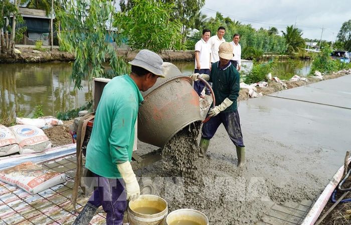 Thi công công trình đường giao thông nông thôn dọc kênh Ô Môi, xã Vĩnh Bình. Ảnh: Văn Sĩ - TTXVN