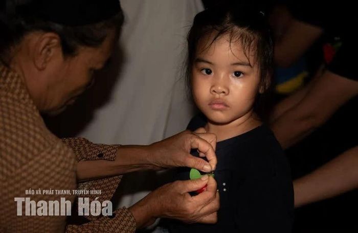 Bà ân cần cài bông hoa nhỏ lên ngực áo cháu, nhẹ nhàng truyền trao hạt mầm hiếu thuận.