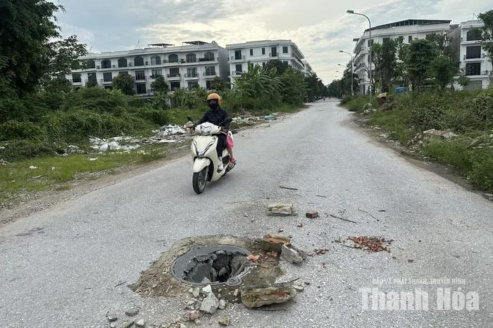 Cách đó không xa, một hố ga khác cũng trong tình trạng hư hỏng, mất nắp và nằm giữa đường. Người dân phải lấy gạch, đá đặt xung quanh để ngăn phương tiện đi vào.
