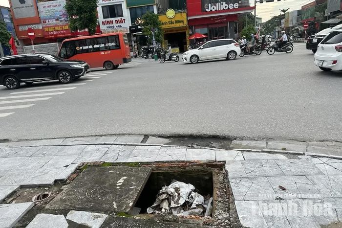 Để hạn chế nguy hiểm, người dân phải tự đặt đất đá, cành cây, thậm chí rác thải xuống các miệng hố lộ thiên. Cách xử lý tự phát này khiến gây tắc nghẽn hệ thống tiêu thoát nước. (Trong ảnh: Nắp cống bị vỡ trên đường Trần Phú, phường Hạc Thành).