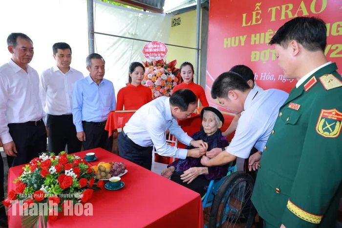 Trưởng Ban Tuyên giáo Trung ương Trịnh Văn Quyết gắn Huy hiệu 80 năm tuổi Đảng cho bà Lê Thị Thủy.