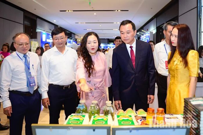 Chủ tịch UBND tỉnh Tô Anh Dũng và các đại biểu nghe giới thiệu về sản phẩm doanh nghiệp trưng bày bên lề hội nghị.