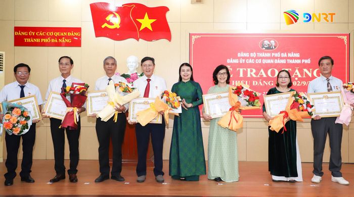 Phó Bí thư chuyên trách Đảng ủy Các cơ quan Đảng thành phố Đặng Thị Lệ Thủy (thứ 4, bên phải sang) trao Huy hiệu 35 năm tuổi Đảng cho các đảng viên. Ảnh: NGỌC PHÚ