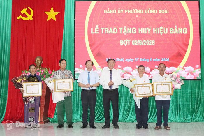 Bí thư Đảng ủy, Chủ tịch HĐND phường Đồng Xoài Vũ Văn Mười (thứ 3 từ phải qua) cùng lãnh đạo Ủy ban MTTQ Việt Nam phường trao Huy hiệu Đảng và tặng hoa cho các đảng viên. Ảnh: Quang Minh
