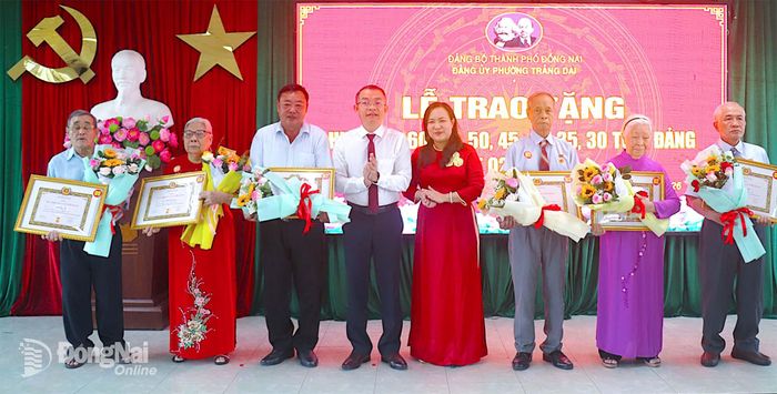 Bí thư Đảng ủy, Chủ tịch HĐND phường Trảng Dài Phan Quang Tuấn và Phó Bí thư Thường trực Đảng ủy phường Trần Nguyễn Thảo Ly trao quyết định và Huy hiệu 60 năm tuổi Đảng cho các đảng viên. Ảnh: An Nhơn