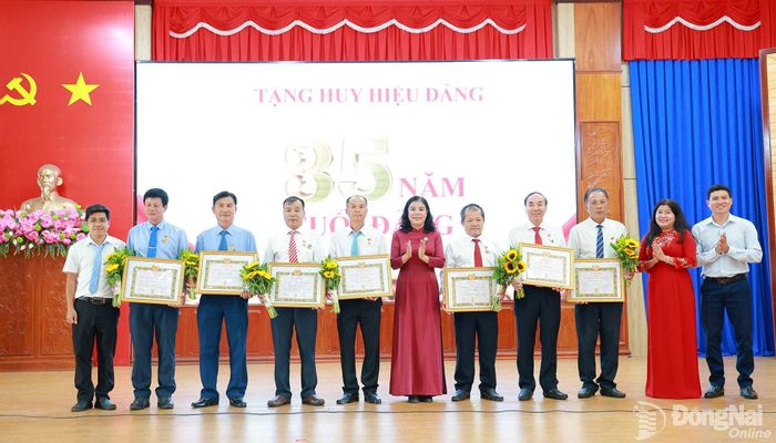 Thành ủy viên, Bí thư Đảng ủy xã Nguyễn Thị Xuân Hòa trao Huy hiệu 35 năm tuổi Đảng cho các đảng viên. Ảnh: Vũ Nguyện