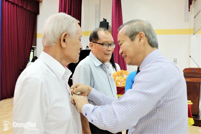 Thành ủy viên, Bí thư Đảng ủy, Chủ tịch HĐND phường Cao Tiến Sỹ trao Huy hiệu 55 năm tuổi Đảng cho 2 đảng viên. Ảnh: Nhật Quang