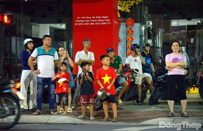 Một gia đình đưa con nhỏ xuống đường, cùng khoác áo đỏ sao vàng hòa vào không khí ăn mừng.