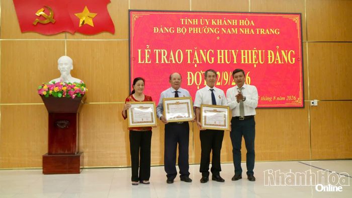 Bí thư Đảng ủy, Chủ tịch HĐND phường Trần Nam Bình trao Huy hiệu 50 năm tuổi Đảng cho các đảng viên.