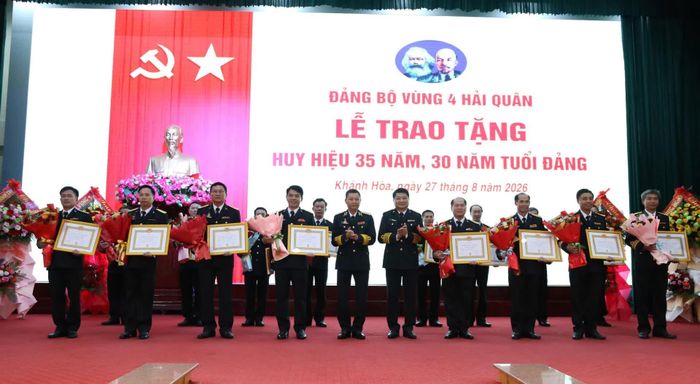 Chuẩn Đô đốc Nguyễn Anh Tuấn và Đại tá Bùi Xuân Bình trao quyết định, tặng hoa chúc mừng các đảng viên nhận Huy hiệu 30 năm tuổi Đảng.
