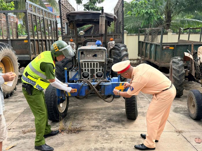 Cán bộ Trạm Cảnh sát giao thông Hàm Tân dán miếng phản quang cho xe tự chế của người dân