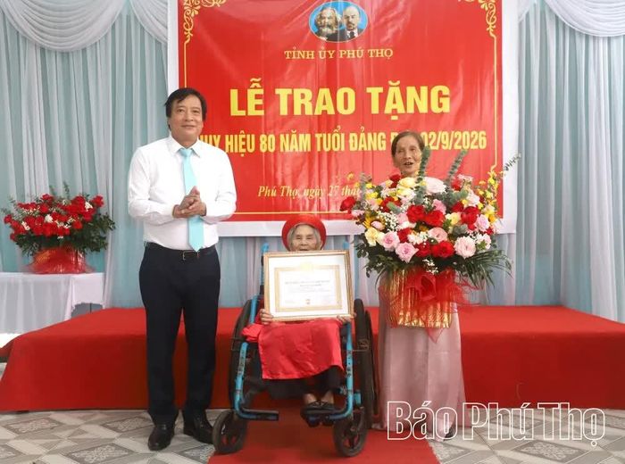 Đồng chí Phó Bí thư Tỉnh ủy Nguyễn Mạnh Sơn chúc mừng và trao Huy hiệu 80 năm tuổi Đảng tặng đồng chí Hoàng Thị Dinh.