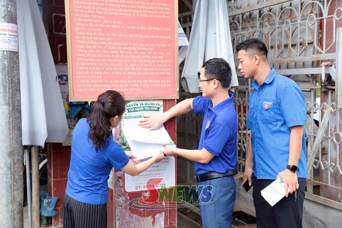 Các đoàn viên dán pano tuyên truyền tại cổng Chợ Trung tâm.