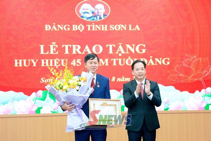 Đồng chí Hoàng Văn Nghiệm trao Huy hiệu 45 năm tuổi Đảng cho đảng viên Cầm Ngọc Minh.
