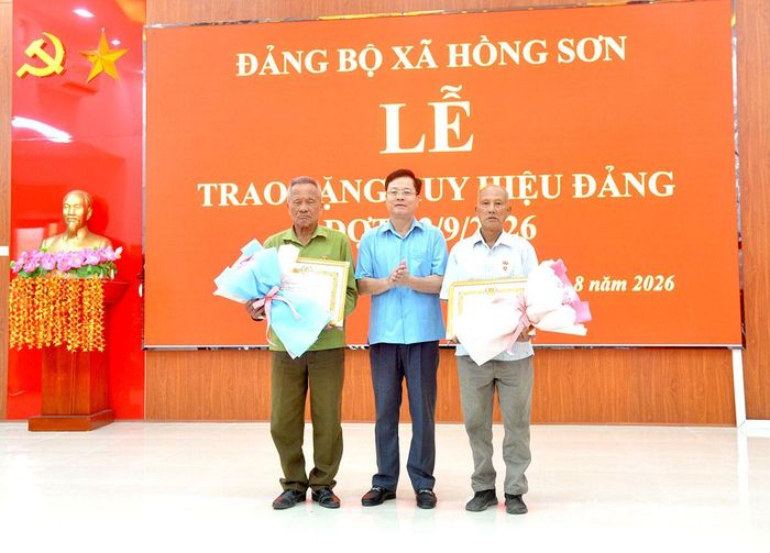 Đồng chí Trần Quang Minh, Trưởng ban Tổ chức Tỉnh ủy trao Huy hiệu 60 năm tuổi Đảng cho các đảng viên thuộc Đảng bộ xã Hồng Sơn.