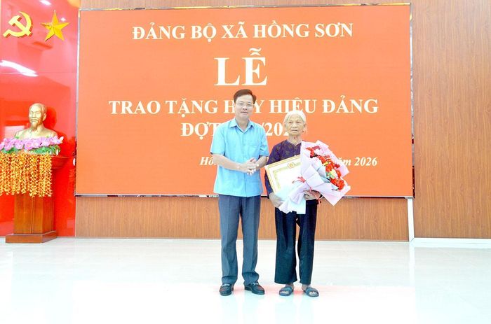 Đồng chí Trần Quang Minh, Trưởng ban Tổ chức Tỉnh ủy trao Huy hiệu 65 năm tuổi Đảng cho đảng viên Đàm Thị Vị, Chi bộ Giếng Bọc, Đảng bộ xã Hồng Sơn.