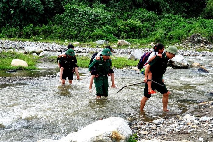 Bộ đội Biên phòng Lào Cai đưa các em học sinh qua suối đến lớp học. Ảnh: Trung Dũng