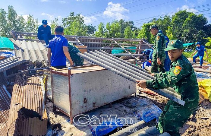 Lực lượng quân sự, biên phòng cùng người dân lân cận hỗ trợ gia đình ông Phan Chí Tâm khắc phục hậu quả sau khi lốc xoáy làm sập nhà.