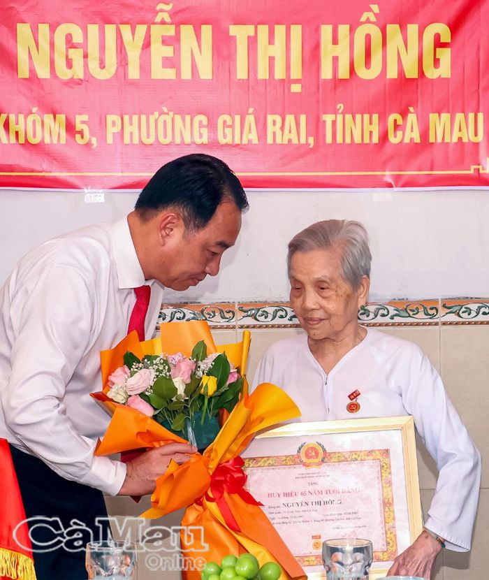  Đồng chí Lữ Quang Ngời, Phó Bí thư Tỉnh uỷ, Chủ tịch UBND tỉnh, trao Huy hiệu 65 năm tuổi Đảng và tặng hoa chúc mừng đảng viên Nguyễn Thị Hồng.