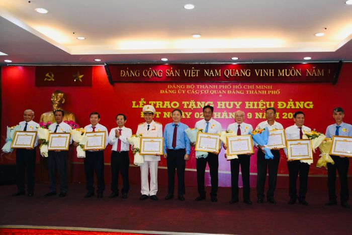 Đồng chí Dương Anh Đức, Ủy viên Ban Thường vụ Thành ủy, Trưởng ban Tuyên giáo Thành ủy và đồng chí Lê Văn Phong - Thành ủy viên, Phó Bí thư Đảng ủy các cơ quan Đảng TPHCM trao Huy hiệu Đảng và tặng hoa chúc mừng các đảng viên