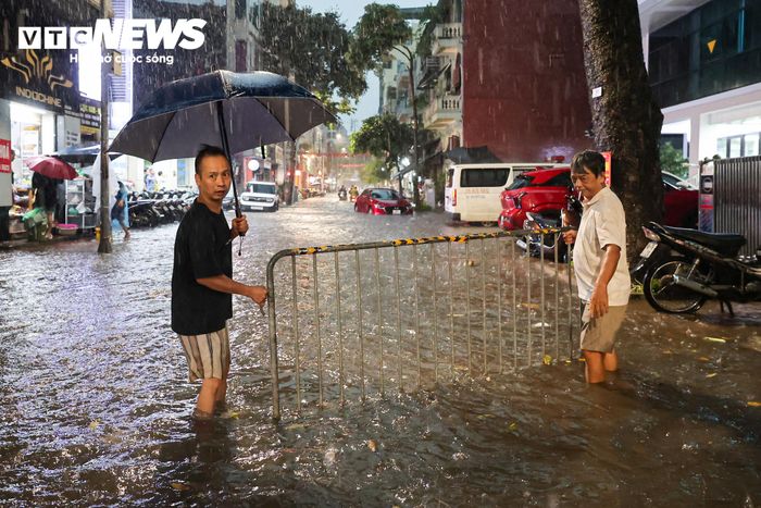 Tại phố Hòe Nhai, mưa lớn khiến nước dồn về, có thời điểm dâng khoảng 40 - 50 cm. Người dân đặt rào chắn để cảnh báo các phương tiện khi đi qua khu vực.