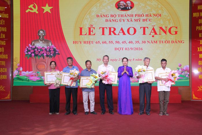 Phó Bí thư Thường trực Đảng ủy xã Mỹ Đức Nguyễn Thị Thúy Hòa trao Huy hiệu Đảng tặng các đảng viên. Ảnh: Biên Phạm