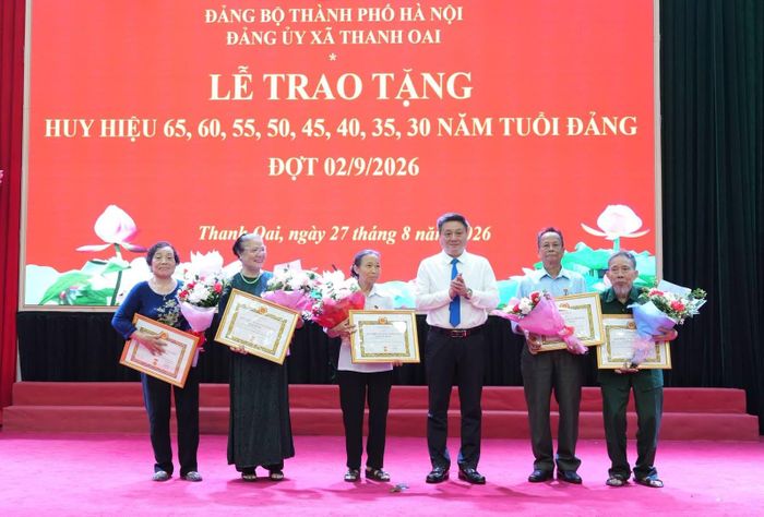 Đồng chí Bùi Hoàng Phan - Bí thư Đảng ủy, Chủ tịch HĐND xã Thanh Oai trao Huy hiệu Đảng tặng các đảng viên. Ảnh: Nguyễn Lý