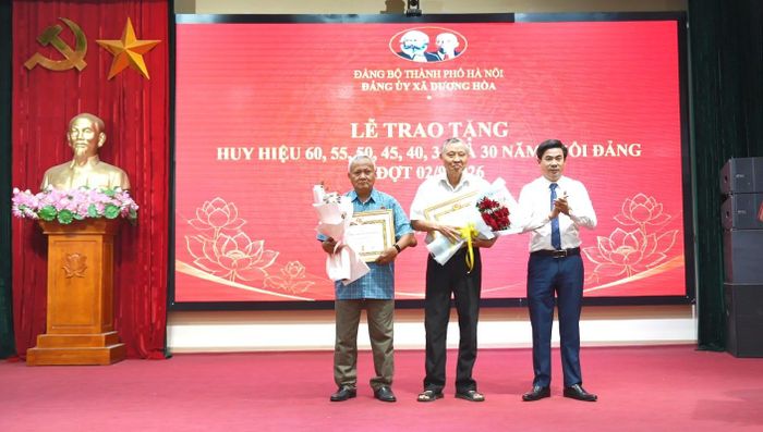 Phó Bí thư Đảng ủy, Chủ tịch UBND xã, Lê Đức Phóng trao Huy hiệu Đảng và chúc mừng các đảng viên. Ảnh: Phượng Nguyễn