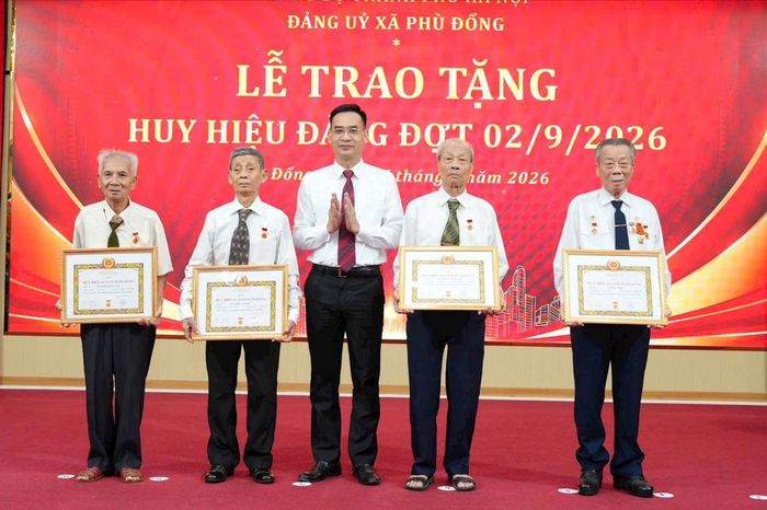 Đồng chí Nguyễn Mậu Quang, Phó Bí thư Thường trực Đảng ủy xã trao Huy hiệu 65 năm tuổi Đảng cho các đồng chí đảng viên. Ảnh: Nguyễn Sơn