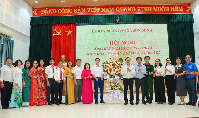 Lãnh đạo xã Sơn Đồng tặng hoa chúc mừng ngành giáo dục xã. Ảnh: NS