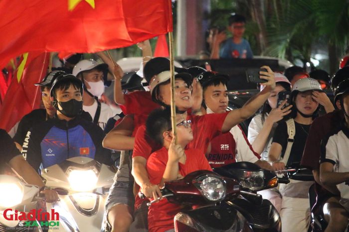 Nhiều nhóm bạn trẻ và các gia đình vừa di chuyển trên xe máy vừa hào hứng sử dụng điện thoại để ghi lại những khoảnh khắc khó quên trong đêm hội bóng đá.