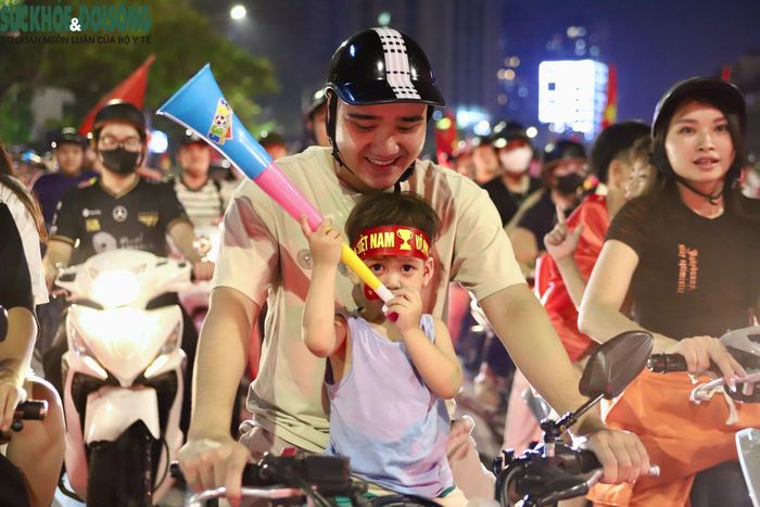 Nhiều em nhỏ được bố mẹ đưa xuống phố, hòa vào dòng người “đi bão” mừng Việt Nam vô địch. (Ảnh Thành Long)