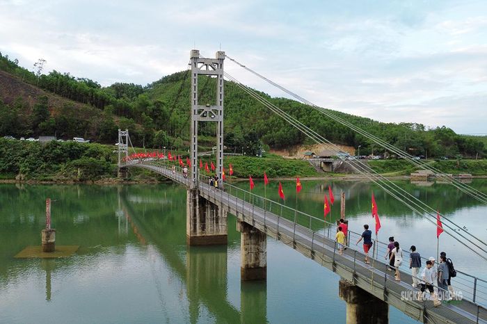Người dân và du khách qua lại trên cầu Bản Mạ. Ảnh: T.Anh