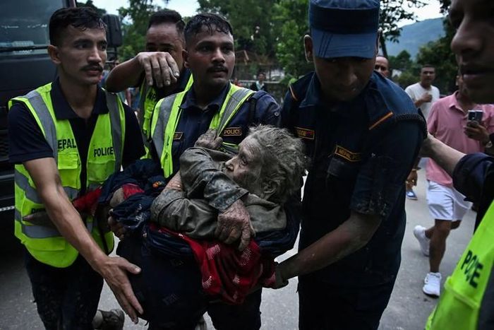 Các nhân viên cứu hộ bế một người sống sót sau trận lũ quét tại huyện Nuwakot, Nepal. Ảnh: Prakash Mathema/Getty Images