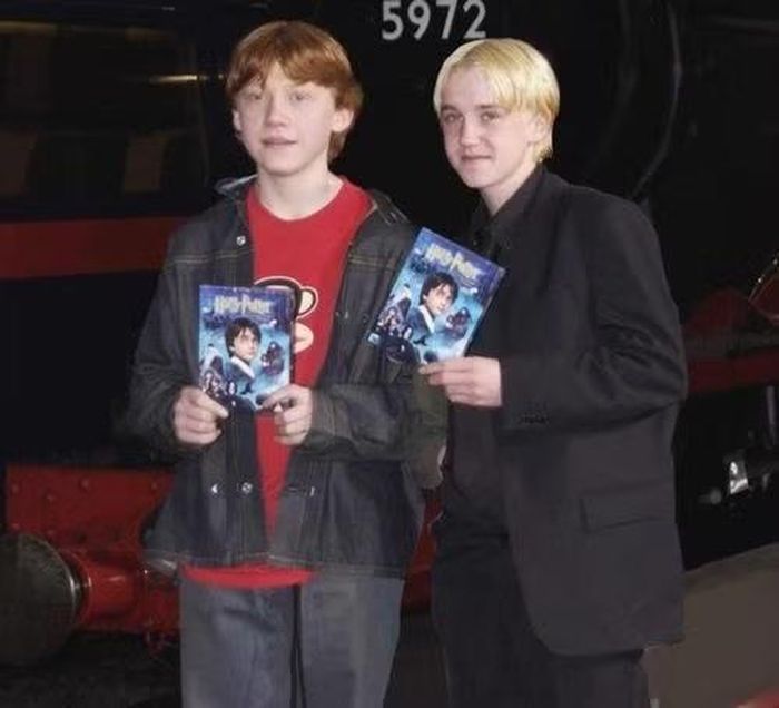 Rupert Grint và Tom Felton cầm trên tay DVD Harry Potter và Hòn Đá Phù Thủy.